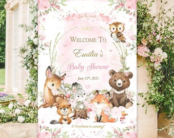 May include: A pink and green woodland themed baby shower welcome sign with a floral design and a group of woodland animals including a deer, fox, owl, rabbit, and bear. The sign says "Welcome to Emilia's Baby Shower June 12th, 2025 A Newborn is coming!"