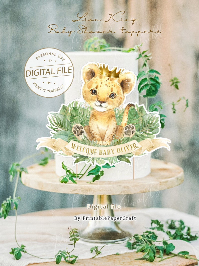 May include: Printable cake topper featuring a cartoon lion cub wearing a gold crown, sitting on green leaves with a banner that reads "Welcome Baby Oliver".