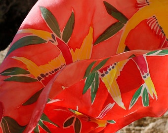 May include: A red silk scarf with a floral pattern in yellow, green, and pink. The scarf is flowing in the wind.