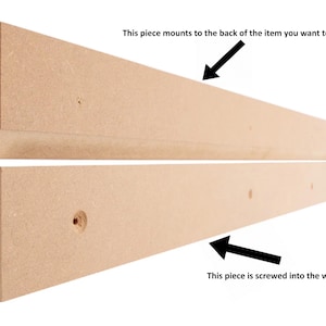 May include: Two pieces of unfinished wood, one with a beveled edge, designed to be mounted to a wall and the back of an item. The top piece is labeled "This piece mounts to the back of the item you want to hand". The bottom piece is labeled "This piece is screwed into the wall".