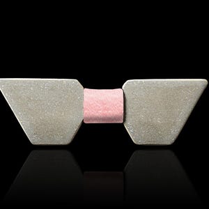 May include: A grey bow tie with a pink bow in the centre. The bow tie is made of a textured material.