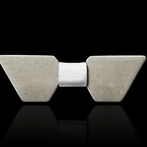 May include: A grey concrete bow tie with a white fabric centre. The bow tie is a modern and minimalist design.