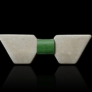 May include: A silver bow tie with a green leather band. The bow tie is made of two triangular pieces that are joined together by the band.