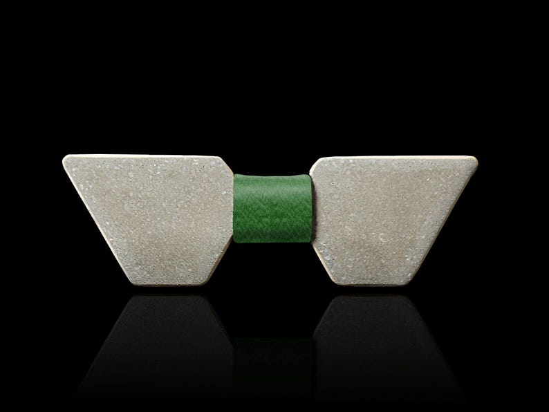 May include: A silver bow tie with a green leather band. The bow tie is made of two triangular pieces that are joined together by the band.