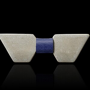 May include: A silver bow tie with a geometric shape and a dark blue leather band.