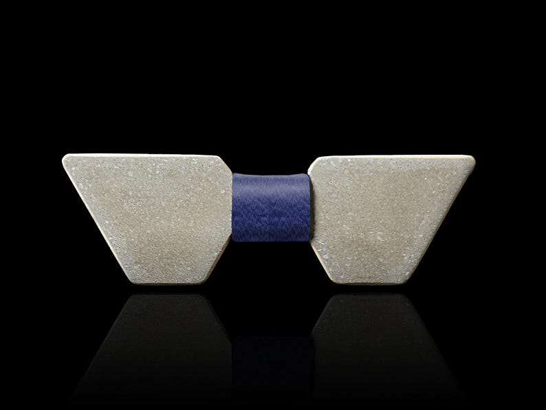 May include: A silver bow tie with a geometric shape and a dark blue leather band.