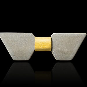 May include: A silver bow tie with a yellow centre. The bow tie is made of two triangular pieces of metal.