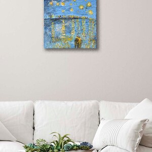 Puede incluir: Una pintura que representa un cielo azul con estrellas amarillas y una silueta oscura de una persona de pie frente a una masa de agua con reflejos amarillos.