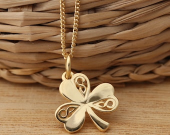 May include: A gold chain necklace with a Celtic knot shamrock pendant. The pendant is detailed with intricate cutouts.