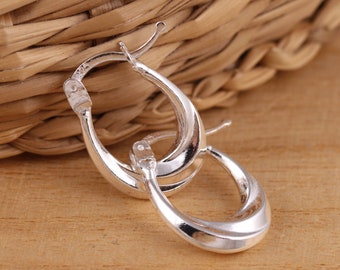 May include: A pair of silver hoop earrings with a smooth, rounded design. The earrings are made of metal and have a polished finish.