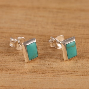 Peut inclure: Une paire de boucles d'oreilles en argent avec des pierres turquoise. Les pierres sont de forme rectangulaire et de couleur bleu clair.
