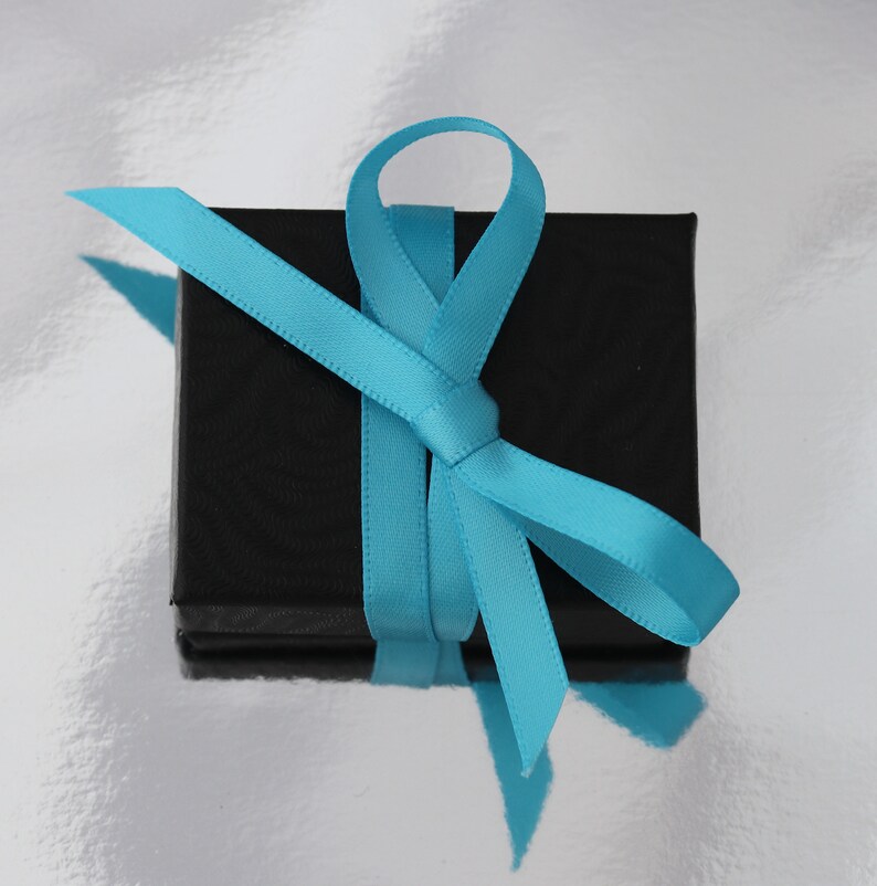 May include: A black gift box tied with a turquoise blue ribbon.
