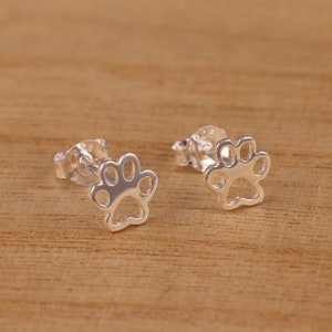 May include: A pair of silver paw print stud earrings. The earrings are small and delicate, and they would make a great gift for any dog lover.