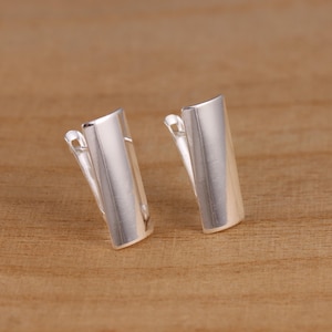 May include: A pair of silver clip-on earrings with a rectangular shape.