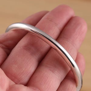Op de afbeelding: Een zilveren armband met een gladde, gepolijste afwerking.