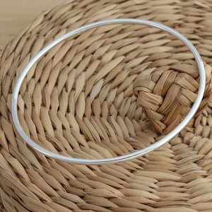 May include: A silver bangle bracelet on a woven background.