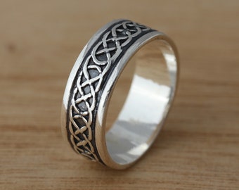 May include: A silver ring with a Celtic knot design. The ring is polished and has a smooth finish.