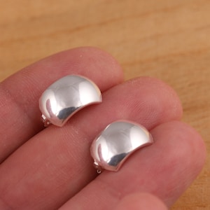 May include: A pair of silver hoop earrings with a smooth, rounded surface.