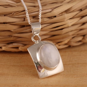 May include: A silver chain necklace with a square pendant featuring a round, iridescent moonstone.