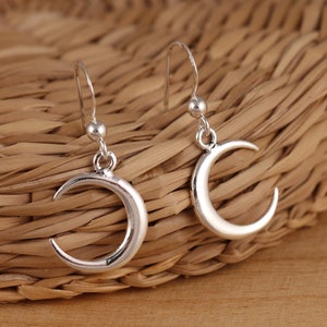 Puede incluir: Un par de pendientes de aro de plata en forma de media luna. Los pendientes tienen un diseño sencillo y son perfectos para el uso diario.