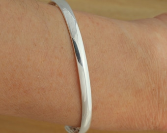 Puede incluir: Un brazalete de plata con un acabado liso y pulido.
