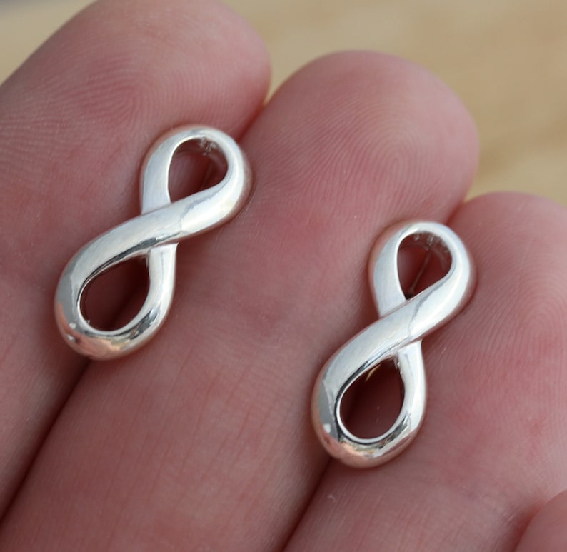 May include: Two silver infinity symbol earrings. The earrings are small and delicate, and they are perfect for everyday wear.