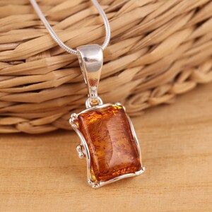 May include: A silver chain necklace with a pendant featuring a rectangular amber stone set in a silver frame.