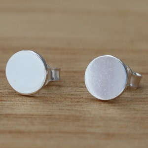 May include: A pair of silver stud earrings with round, smooth, flat fronts.