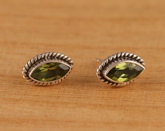 Puede incluir: Un par de pendientes de plata con piedras preciosas verdes en forma de marquesa engastadas en un diseño de cuerda trenzada.