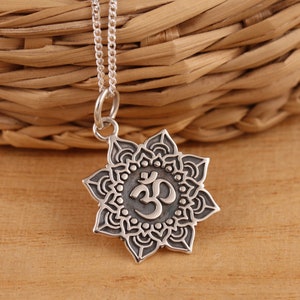 Puede incluir: Collar de plata con un colgante con el símbolo Om rodeado de un diseño de mandala detallado.