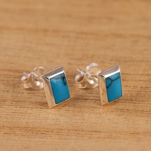 Puede incluir: Un par de pendientes de plata con piedras turquesa rectangulares.