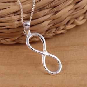 Peut inclure: Un collier avec un pendentif en forme de symbole infini en argent. Le pendentif est un design simple et élégant avec une finition lisse.