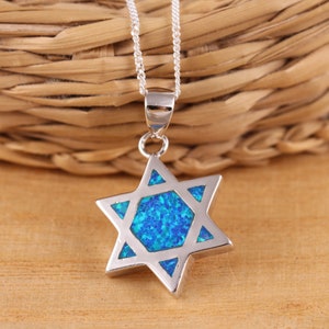 Puede incluir: Un collar de cadena de plata con un colgante de estrella de David de ópalo azul.