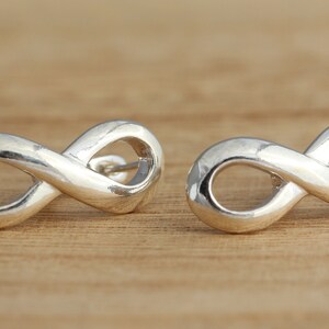 May include: A pair of silver infinity symbol earrings. The earrings are small and delicate, and they are perfect for everyday wear.