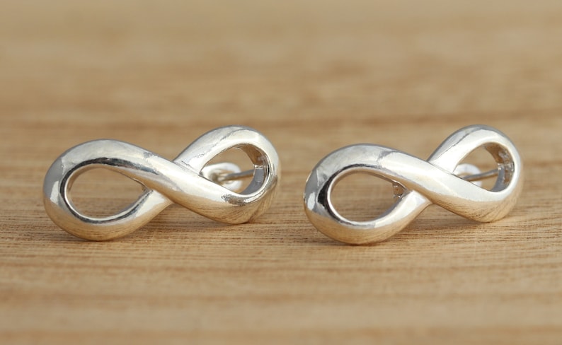 May include: A pair of silver infinity symbol earrings. The earrings are small and delicate, and they are perfect for everyday wear.