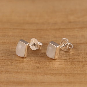 May include: A pair of silver earrings with white moonstone rectangular stones.