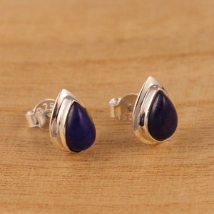 Könnte beinhalten: Ein Paar silberne Tropfenohrringe mit blauen Lapislazuli-Steinen.