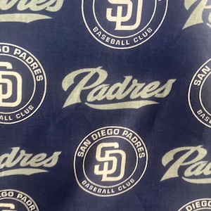 May include: Navy blue fabric with a repeating pattern of the San Diego Padres baseball team logo and the word "Padres". The logo features the letters "SD" within a circle, along with the text "San Diego Padres Baseball Club".