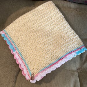 Yellow crochet baby blanket with a shell scallop border in variegated colors of pink,teal,yellow,and white