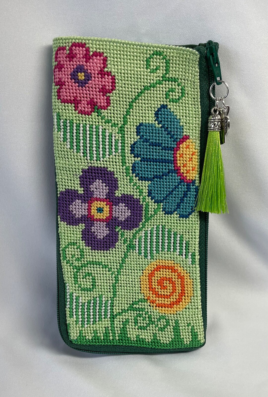 A Finished Needlepoint Eyeglass Case With Flowers on a Green Background