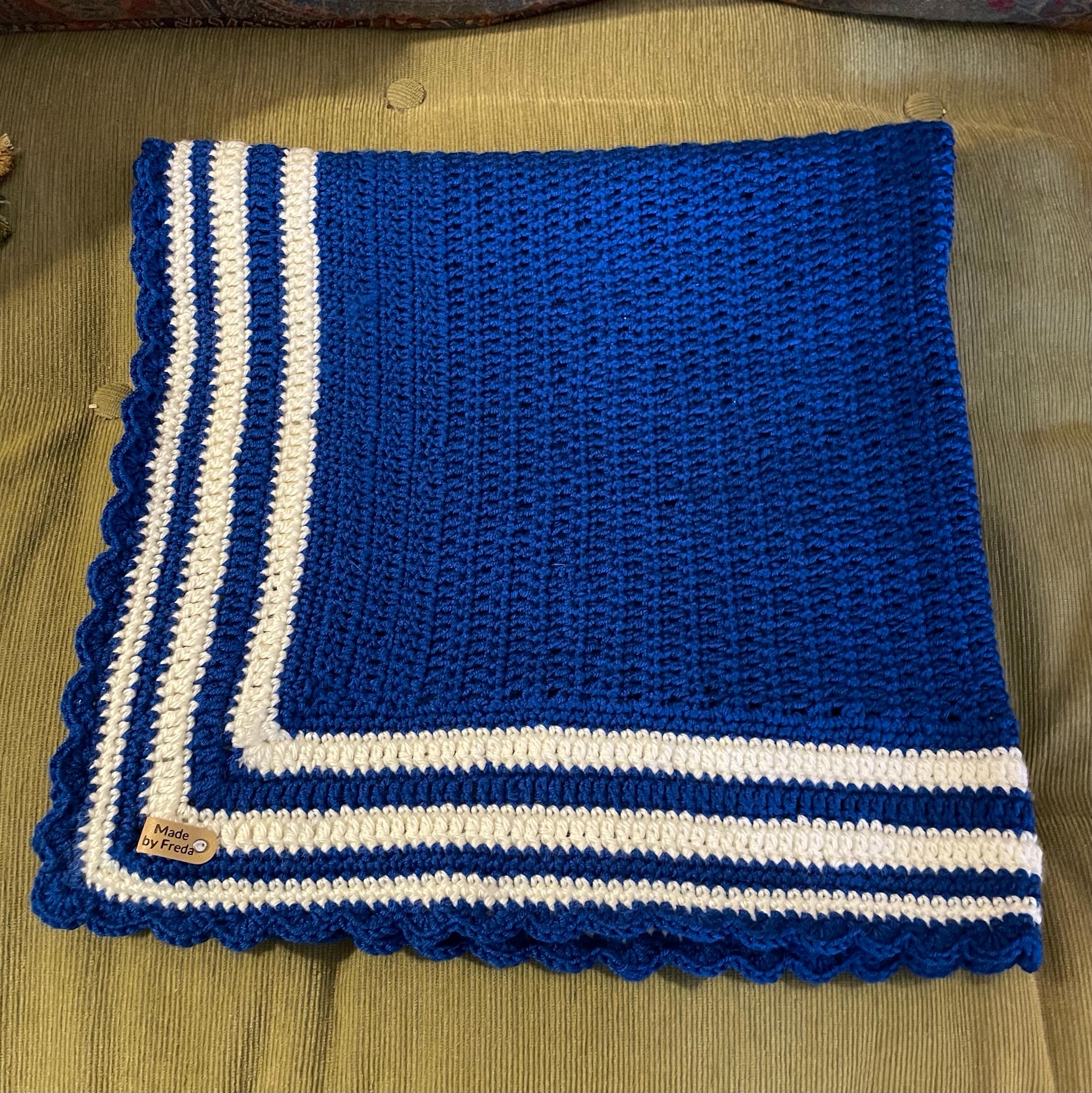 A beautiful deep navy blue croheted baby blanket with a navy blue and white border.