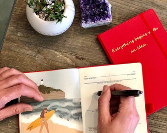 May include: An open red journal with the text "Everything begins with an idea..." on the cover. The journal is open to a page with an illustration of a woman surfing and the text "law of movement: EVERYTHING IS MOVING NOTHING BESTS YOU ARE GETTING BETTER OR GETTING WORSE. GROW OR DIE."