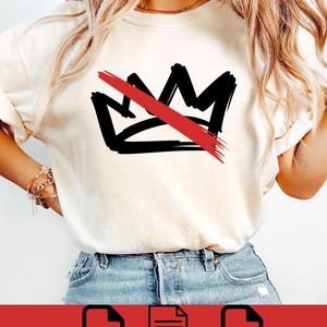 May include: Cream-colored t-shirt featuring a black crown design with a red slash through it. The graphic is a bold, hand-drawn style. The shirt is paired with blue jeans. The image also includes PNG, SVG, and EPS file icons.