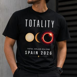 May include: A black short-sleeved t-shirt featuring a graphic of a solar eclipse progression. The text reads "TOTALITY" at the top and "TOTAL SOLAR ECLIPSE SPAIN 2026" at the bottom, with a small star icon between two horizontal lines.