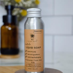 May include: A silver aluminum bottle with a brown label that reads "Peppermint", "ME Mother Earth", "irstile", "LIQUID SOAP", "Earth Friendly", "Natural Ingredients", "Guilt-Free Packaging", "Multipurpose | Travel Size", "3 oz", "@memotherearth", "memotherearthbrand.com", "Made in the USA".