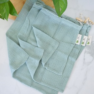 May include: Three light blue reusable mesh produce bags with the text "HOME" and a small tree logo printed on the tags.