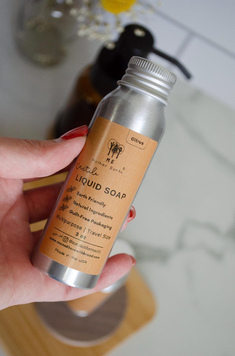 May include: A silver aluminum bottle with a brown label that reads "ME Mother Earth Castile LIQUID SOAP Earth Friendly Natural Ingredients Guilt-Free Packaging Multipurpose | Travel Size 3 oz onst@me.motherearth www.memotherearthbrand.com Made in the USA" and the word "Citrus" at the top of the label.