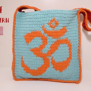 Puede incluir: Una bolsa de mano de crochet con un símbolo Om naranja sobre un fondo azul claro. La bolsa tiene una correa roja y naranja.