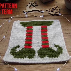 May include: Crocheted elf legs square with green boots, red and green striped legs, and a white background.
