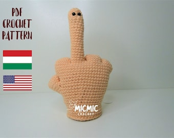 May include: Crochet pattern for a middle finger amigurumi doll. The doll is peach colored with black eyes and the text "MICMIC CROCHET" is on the palm.